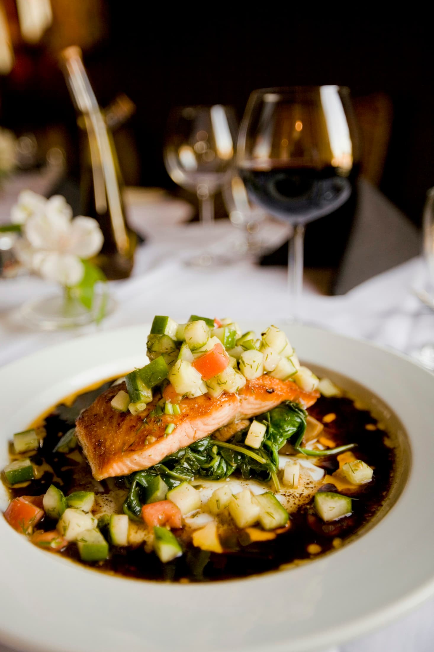 A plated salmon dinner in warm, moody restaurant light